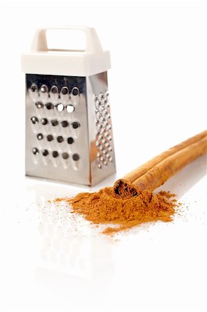 simsearch:400-04791848,k - Sticks, powder of cinnamon and grater reflected on the white background. Shallow DOF Photographie de stock - Aubaine LD & Abonnement, Code: 400-04945043