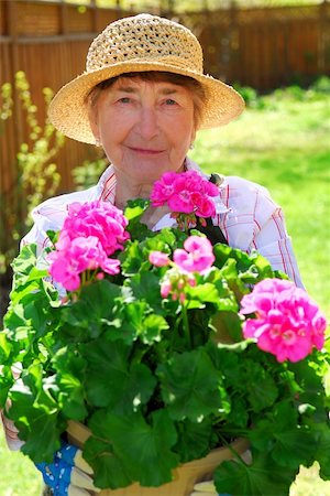 simsearch:400-04439731,k - Smiling senior woman holding a pot with flowers in her garden Photographie de stock - Aubaine LD & Abonnement, Code: 400-04946302