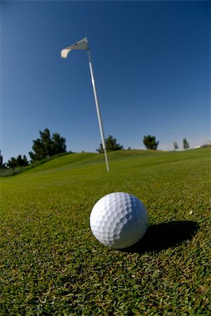 simsearch:400-03975619,k - Image detail of golf ball in foreground with flag in background and deep blue sky Stock Photo - Budget Royalty-Free & Subscription, Code: 400-04949810