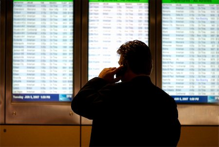 simsearch:400-05212862,k - Image of a businessman on cell phone in airport in front of arrival and departure screens Stock Photo - Budget Royalty-Free & Subscription, Code: 400-04949823