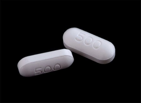 Two white, oval shaped 500 milligram tablets, isolated on black. Foto de stock - Super Valor sin royalties y Suscripción, Código: 400-04940347