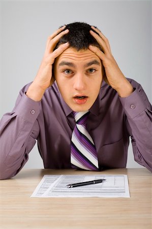 Shocked man at the desk. There's some papers on the desk and a pen. (paper's form is copyright free) Stock Photo - Budget Royalty-Free & Subscription, Code: 400-04940898