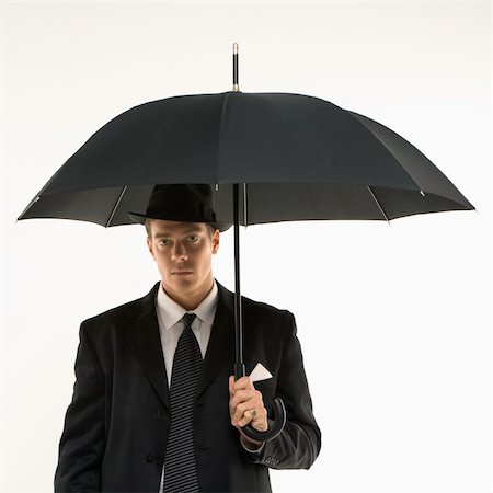 simsearch:400-03924472,k - Caucasian mid-adult businessman wearing fedora holding umbrella  and looking at viewer. Photographie de stock - Aubaine LD & Abonnement, Code: 400-04954791