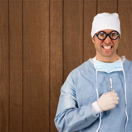simsearch:400-03924532,k - Mid-adult Caucasian male  surgeon wearing thick glasses and holding scalpel smiling maniacally. Stock Photo - Budget Royalty-Free & Subscription, Code: 400-04954800
