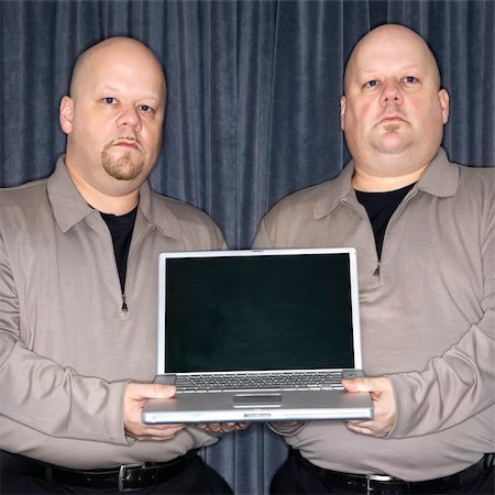 simsearch:400-03926822,k - Caucasian bald identical twin men holding a laptop computer and looking at viewer. Stock Photo - Budget Royalty-Free & Subscription, Code: 400-04956076