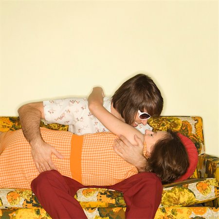 Caucasian mid-adult couple smiling and embracing on colorful retro sofa. Stockbilder - Microstock & Abonnement, Bildnummer: 400-04956219