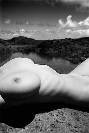 simsearch:400-03925003,k - Close up torso of young adult nude Caucasian woman lying on boulder on rocky Maui coast. Photographie de stock - Aubaine LD & Abonnement, Code: 400-04956640