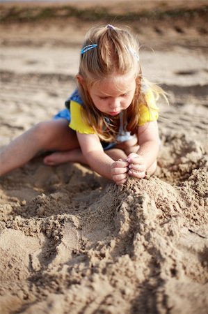 family relaxing with kids in the sun - Cute kid playing with sand on a beach Stock Photo - Budget Royalty-Free & Subscription, Code: 400-04956650