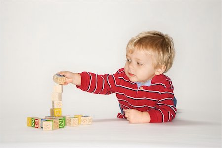 Studio portrait of Caucasian boy playing with toy blocks. Foto de stock - Super Valor sin royalties y Suscripción, Código: 400-04957056
