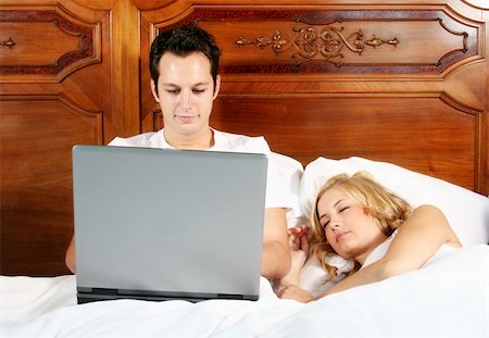 a attractive young man is working with his notebook, while his girlfriend is sleeping Stock Photo - Budget Royalty-Free & Subscription, Code: 400-04957200