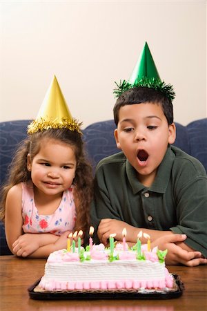 simsearch:400-04452450,k - Hispanic girl and boy wearing party hats preparing to blow candles out on birthday cake. Stock Photo - Budget Royalty-Free & Subscription, Code: 400-04957399