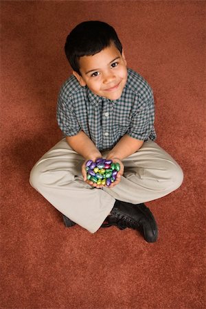 simsearch:400-04452450,k - Hispanic boy sitting on floor holding chocolate candy eggs in his hands looking up at viewer smiling. Stock Photo - Budget Royalty-Free & Subscription, Code: 400-04957392