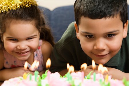 simsearch:400-04452450,k - Hispanic girl and boy leaning in close looking at lit candles on birthday cake and smiling. Stock Photo - Budget Royalty-Free & Subscription, Code: 400-04957400