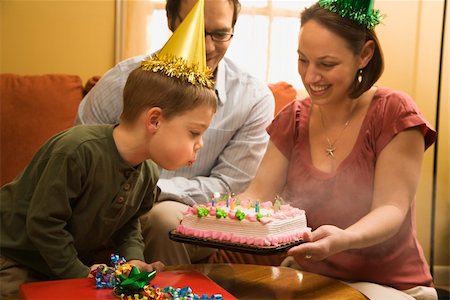 Caucasian boy in party hat blowing out candles on birthday cake with family watching. Stock Photo - Budget Royalty-Free & Subscription, Code: 400-04957434