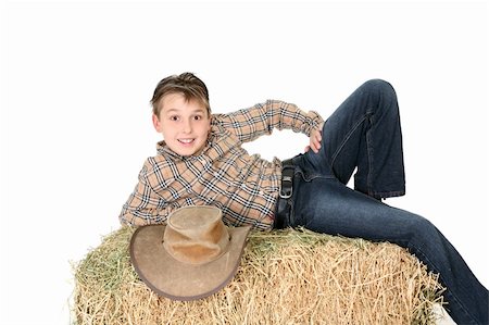 A boy from the country lays casually on a hay bale and smiles.  White background. Photographie de stock - Aubaine LD & Abonnement, Code: 400-04958007