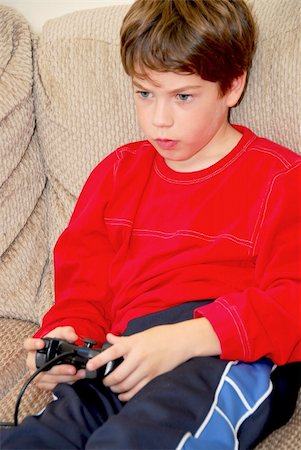 simsearch:400-05059261,k - Young boy playing a video game sitting on a couch Stock Photo - Budget Royalty-Free & Subscription, Code: 400-04958113