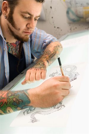 Caucasian male tattoo artist drawing tattoo on light table. Fotografie stock - Microstock e Abbonamento, Codice: 400-04950324