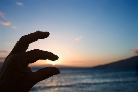 simsearch:400-04006465,k - Hand in foreground with fingers around sunrise over the coast of Kihei, Maui, Hawaii, USA. Photographie de stock - Aubaine LD & Abonnement, Code: 400-04951056