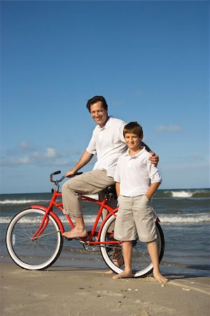 simsearch:400-04953081,k - Caucasian father and pre-teen boy standing on beach with bicycle. Foto de stock - Royalty-Free Super Valor e Assinatura, Número: 400-04953078