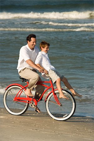 simsearch:400-04953081,k - Caucasian mid-adult man riding bicycle on beach with pre-teen boy on handlebars. Foto de stock - Royalty-Free Super Valor e Assinatura, Número: 400-04953081