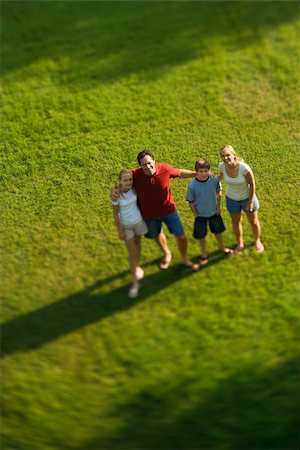 simsearch:400-03923192,k - Caucasian family of four standing on lawn with arms around each other. Foto de stock - Super Valor sin royalties y Suscripción, Código: 400-04953599