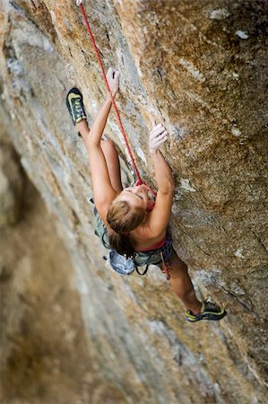 An eager female climber on a steep rock face looks for the next hold - viewed from above.  Shallow depth of field is used to isolated the climber with the focus on the head. Stock Photo - Budget Royalty-Free & Subscription, Code: 400-04966384