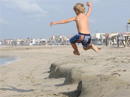 Boy Child jumpimg on the beach.Really catching some ocean air ! Stockbilder - Microstock & Abonnement, Bildnummer: 400-04968990