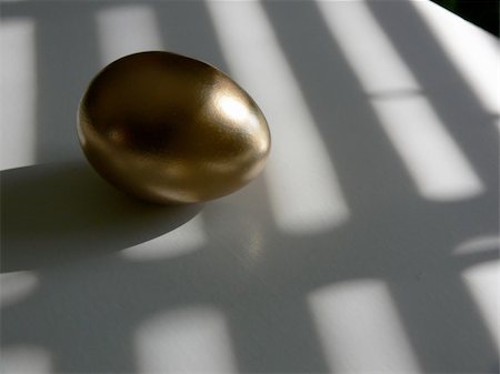 simsearch:400-04555295,k - Golden egg on a white tabletop, with patterns of light and shadow laying across both. Taken with a Panasonic FZ30 Lumix. Stock Photo - Budget Royalty-Free & Subscription, Code: 400-04960782