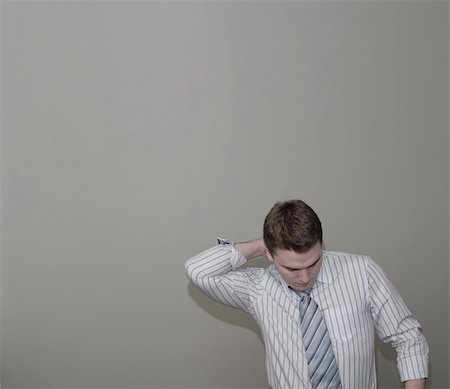 Young man in a dress shirt, rubbing a sore neck, with a green background. Saturation of colours has been reduced, and strong shadows have been left in for effect. There is lots of room for text above and to the left. Stock Photo - Budget Royalty-Free & Subscription, Code: 400-04960810
