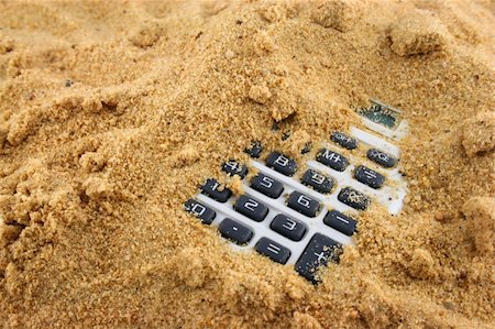 Calculator buried in the sand with numbers showing Stock Photo - Budget Royalty-Free & Subscription, Code: 400-04963130