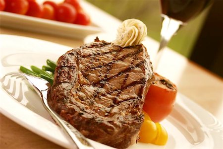 12oz ribeye steak topped with truffle butter and grilled tomato. Served with red wine. Shallow DOF Stock Photo - Budget Royalty-Free & Subscription, Code: 400-04976845