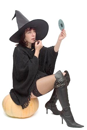 Pretty witch sitting on large pumpkin and making up to prepare for Halloween Stock Photo - Budget Royalty-Free & Subscription, Code: 400-04977423