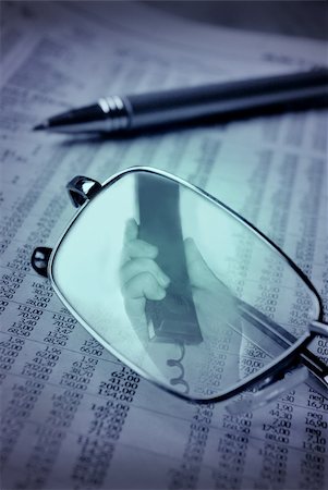 Blue toned image of a financial report, phone in a hand reflects in the glasses Stock Photo - Budget Royalty-Free & Subscription, Code: 400-04978042