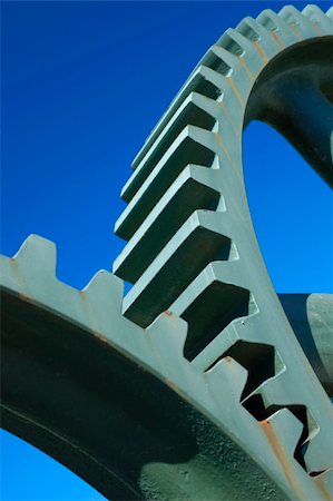 Two old interlocking gear wheels,  slightly rust-streaked, from some unidentifiable piece of machinery, set against a clear blue sky. Space for text. Stock Photo - Budget Royalty-Free & Subscription, Code: 400-04979727