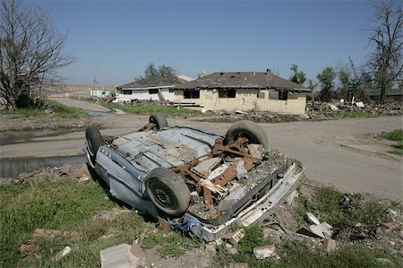 damage house of hurricane katrina - A heavily damaged and overturned car near the Industrial Canal in the Ninth Ward of New Orleans. Houses off their foundations sit in the background. Photographie de stock - Aubaine LD & Abonnement, Code: 400-04971934