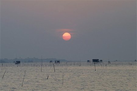 Cloudy sunset at Chonburi on Thailand's eastern seaboard with fishermens huts standing in the shallow waters Photographie de stock - Aubaine LD & Abonnement, Code: 400-04973035
