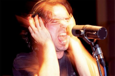 rock singer screaming into mic - An aggressive music singer recording in a studio.  Lots of mood and atmosphere created with timed exposure with hand-held flash. (some film grain because of the 1600 ISO film used) Stock Photo - Budget Royalty-Free & Subscription, Code: 400-04973547