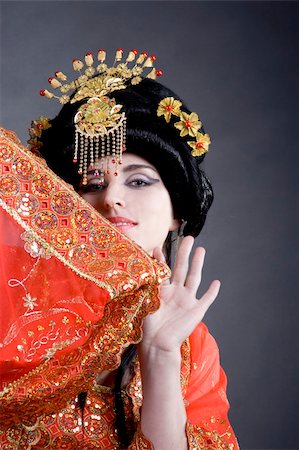 Asian princess hiding behind her embroidered golden red dress. Wearing a golden crown and having a playful look. Fotografie stock - Microstock e Abbonamento, Codice: 400-04984025