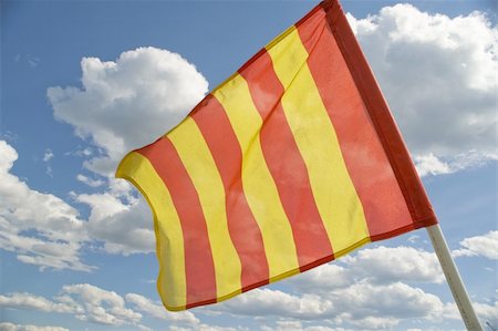 The orange striped flag on a background of the dark blue sky with clouds is yellow. Foto de stock - Royalty-Free Super Valor e Assinatura, Número: 400-04984386