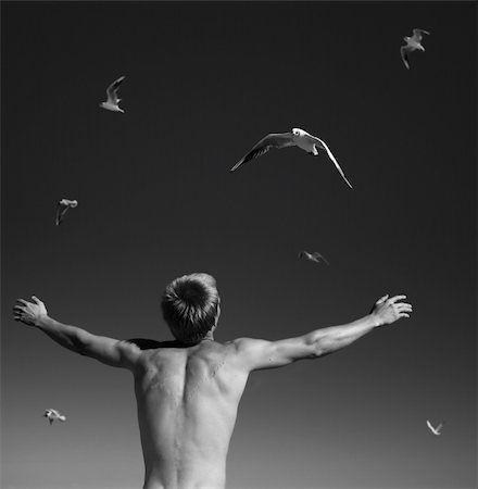 The Young man raises the hands and greets the sea gull, which flying on the sky. Fotografie stock - Microstock e Abbonamento, Codice: 400-04985446