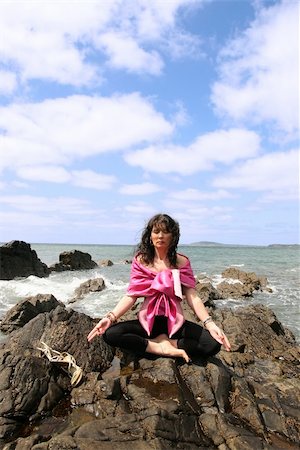 simsearch:400-04985470,k - beautiful woman meditating on the rocks in ireland with her eyes closed, in the lotus position, showing a healthy way to live a happy and relaxed lifestyle in a world full of stress Fotografie stock - Microstock e Abbonamento, Codice: 400-04985468