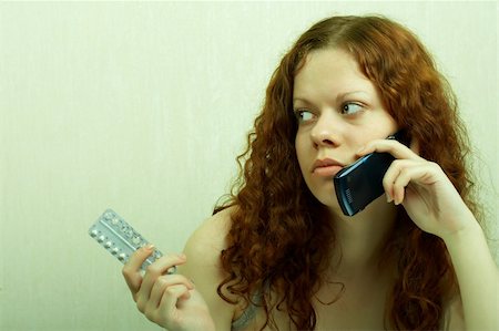 The girl in confusion holds contraceptive tablets in hands and calls by phone Stock Photo - Budget Royalty-Free & Subscription, Code: 400-04985614