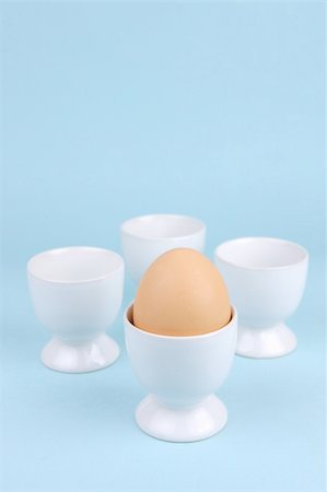 Hard boiled eggs and egg cups isolated against a blue background Stock Photo - Budget Royalty-Free & Subscription, Code: 400-04985618