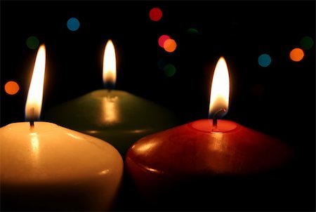 Three Christmas candles up close, with festive lights in the background. Stockbilder - Microstock & Abonnement, Bildnummer: 400-04989539