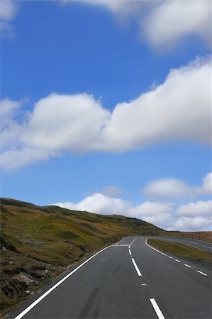 simsearch:400-03984857,k - Empty down hill road in mountains with a dangerous right hand bend, with grass verges to either side, on a blue sky day with cumulus clouds. Located in the Brecon Beacons National Park, Wales, United Kingdom, Foto de stock - Super Valor sin royalties y Suscripción, Código: 400-04980849