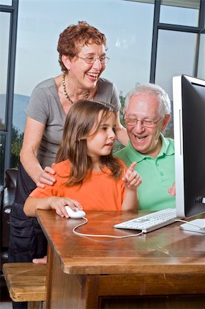 grandparents and granddaughter with computer at home Fotografie stock - Microstock e Abbonamento, Codice: 400-04995835