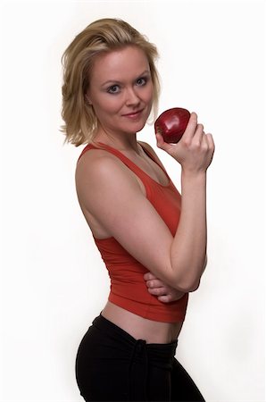 physical fit food - Attractive blond woman in great physical shape wearing black tights and red workout top standing on white holding a red apple in hand Stock Photo - Budget Royalty-Free & Subscription, Code: 400-04999320