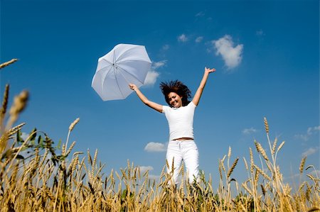 Happy young girl jumping for joy with umbrella in the field Stock Photo - Budget Royalty-Free & Subscription, Code: 400-04990372