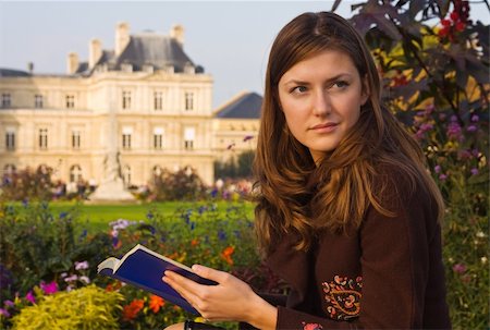 young woman in coat sitting in a park with booklet under evening sunlight Photographie de stock - Aubaine LD & Abonnement, Code: 400-05006482