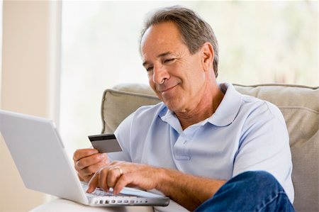 simsearch:400-05000471,k - Man in living room with laptop and credit card smiling Foto de stock - Royalty-Free Super Valor e Assinatura, Número: 400-05000469